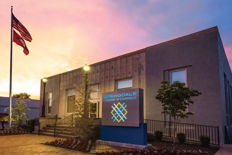 The Springdale Chamber of Commerce building at dusk, with the American and Arkansas flags flying out front.